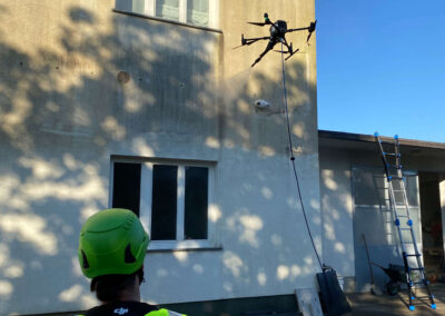 Operater SANDEX nadzira dron med čiščenjem fasade poslovne stavbe.